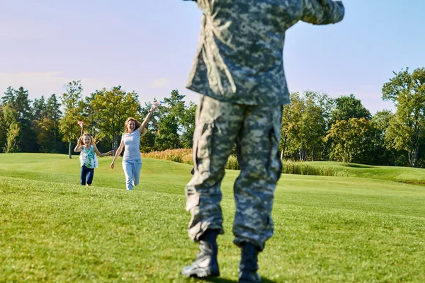 Soldado de vista trasera se encuentra con su familia al aire libre . — Foto de Stock