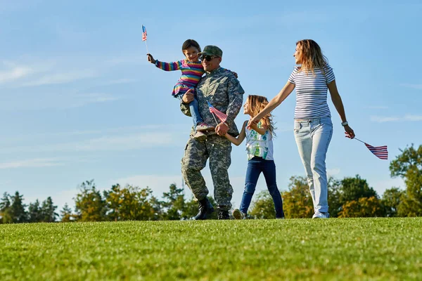 Soldat avec sa famille marchent avec des drapeaux américains . — Photo