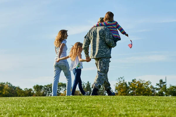后视图士兵和他的家人走在草地上. — 图库照片