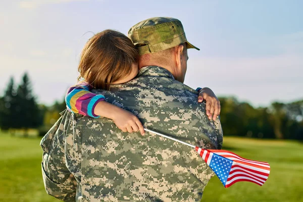 Little girl is hugging his fathger US soldier.