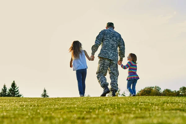 Soldado caminando con niñas pequeñas cogidas de la mano . — Foto de Stock