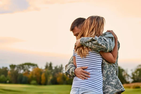 Soldado está abrazando a una mujer al aire libre . — Foto de Stock