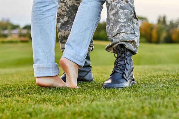 Close up stivali soldato e fidanzata con piedi nudi . — Foto Stock