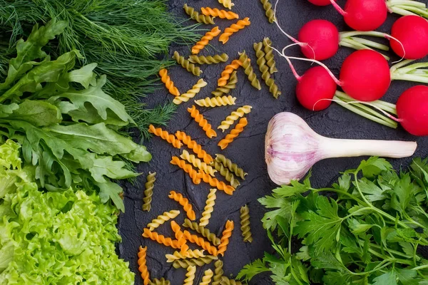 Uncooked pasta with fresh vegetables and herbs.