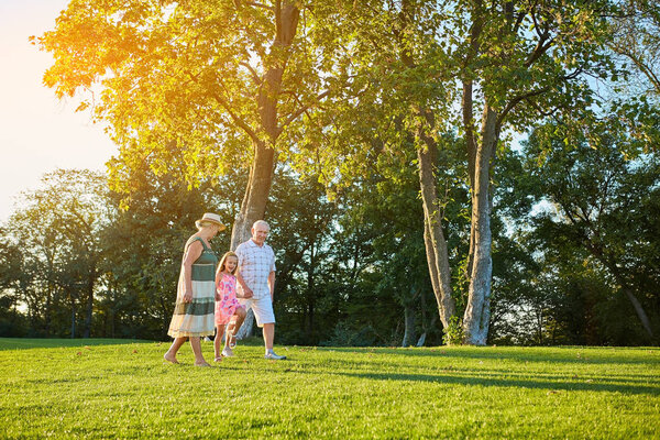 Seniors with grandchild walking outdoors.