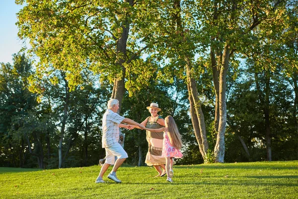 Дівчина з бабусею і дідусем танцює на відкритому повітрі . — стокове фото