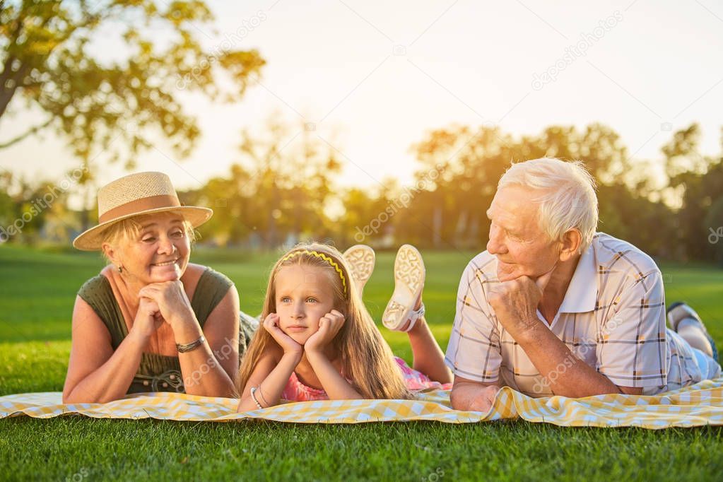Girl with grandparents lying outdoors.