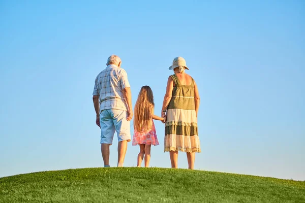 Meisje met grootouders, hemelachtergrond. — Stockfoto