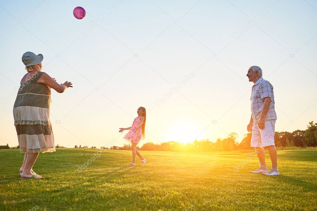 Seniors with grandchild playing ball.