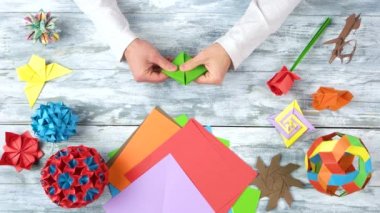 El yeşil kağıttan origami yapıyor.