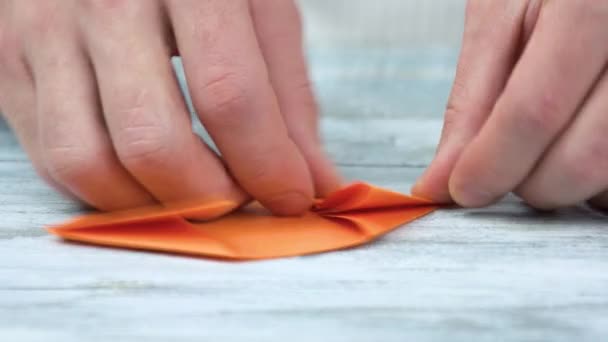 Hände falten Origami aus orangefarbenem Papier. — Stockvideo