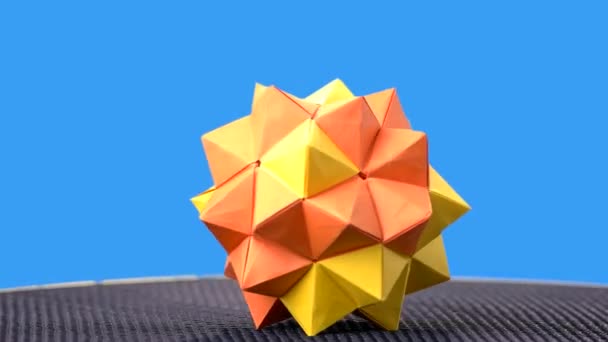 Gelbe Origami-Kugel auf blauem Hintergrund. — Stockvideo