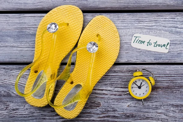 Yellow flip-flops and bell alarm clock.