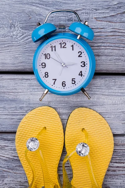 Gele slippers en blauwe wekker. — Stockfoto