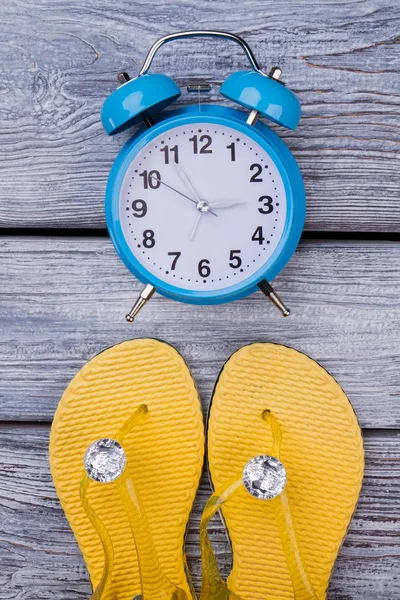 Gelbe Flip Flops und blauer Wecker. — Stockfoto