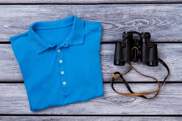 Blue polo t shirt and binoculars.