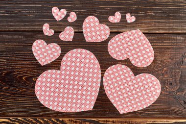 Kağıt kalpleri ile kahverengi ahşap zemin.