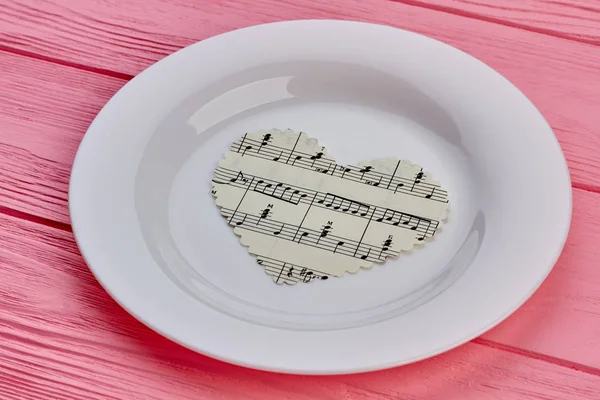 Paper heart with music notes on plate.