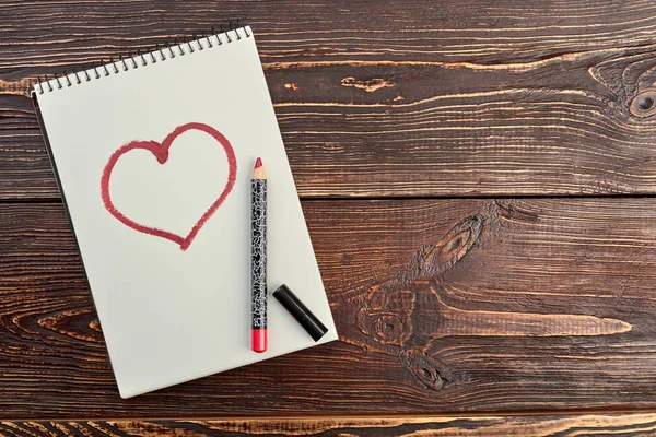 Red pencil and a drawn heart.