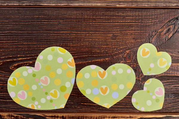 Green paper hearts on brown wood. — Stock Photo, Image