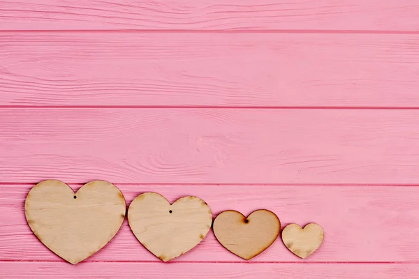 Cuatro corazones de madera contrachapada sobre fondo colorido . — Foto de Stock