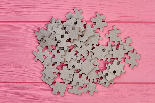 Heap of jigsaw puzzles on wooden background.