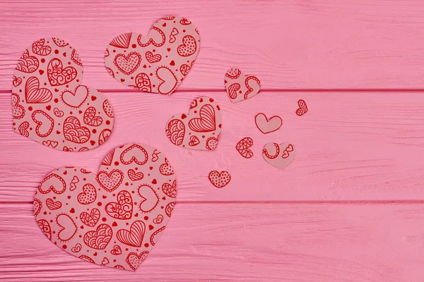 Decorative paper hearts on wooden background.