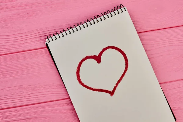 Corazón dibujado con lápiz labial rojo en bloc de notas de papel . —  Fotos de Stock