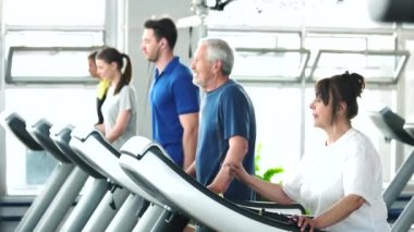 Spor salonunda koşu bandı üzerinde çalışan kadın kıdemli.