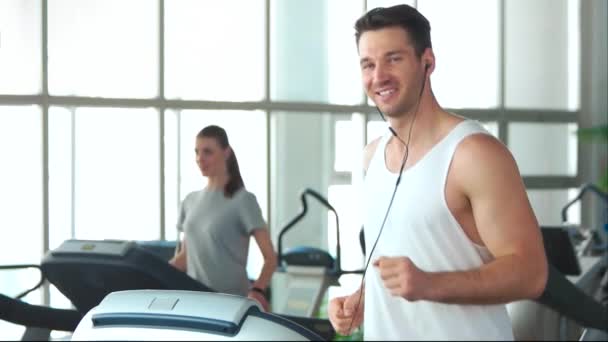 Hombre atlético sonriente corriendo en la cinta . — Vídeos de Stock