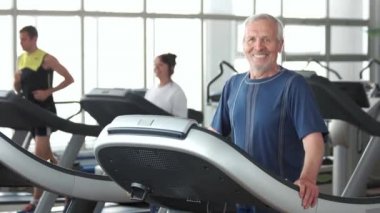 Gülümseyen yaşlı adam spor salonunda egzersiz.