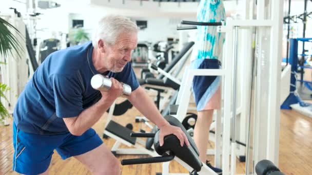 Uomo anziano che solleva manubri in palestra moderna . — Video Stock