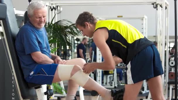 Mannen inslagning med bandage ben av äldre man. — Stockvideo