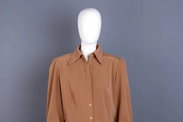 Female mannequin in brown shirt with collar.