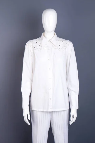 Mannequin wearing white shirt and trousers.