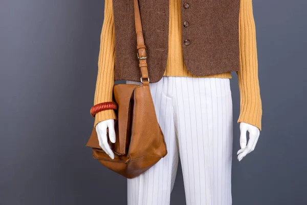 Sweater, waistcoat, handbag on female mannequin.