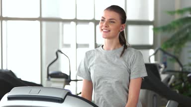 Gülümseyen kız bir koşu bandı üzerinde çalışan.