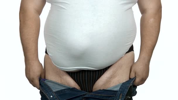 Gordo caucásico hombre tratando de poner en pequeño jeans . — Vídeos de Stock