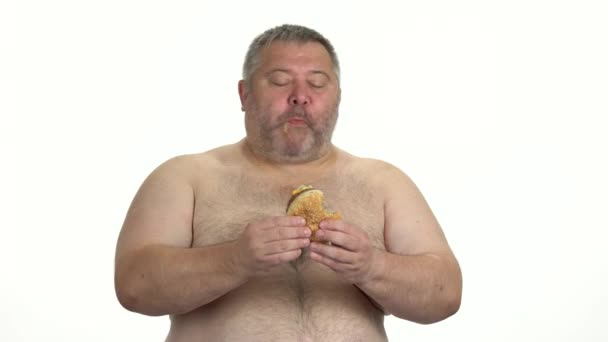 Hombre gordo disfrutando de hamburguesa sobre fondo blanco . — Vídeo de stock