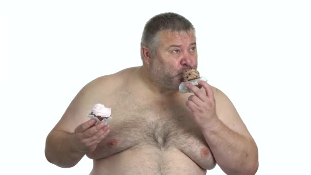 Obez adam beyaz arkaplanda keklerin tadını çıkarıyor. — Stok video