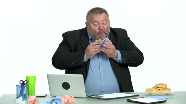 オフィスでデスクトップに座っている間にハンバーガーを楽しむビジネスマン. — ストック動画