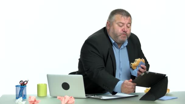 Overweight businessman eating burger at his workplace. — Stock Video