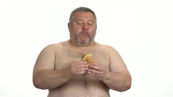 Hombre gordo disfrutando de hamburguesa sobre fondo blanco . — Vídeos de Stock