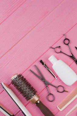 Pembe arka planda kuaför araçları.