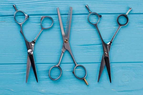 Set of hairdressing scissors on blue wooden background.