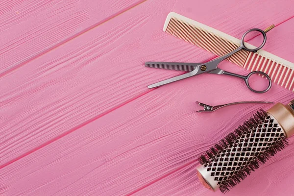 Peignes et ciseaux de coiffeur sur fond rose . — Photo