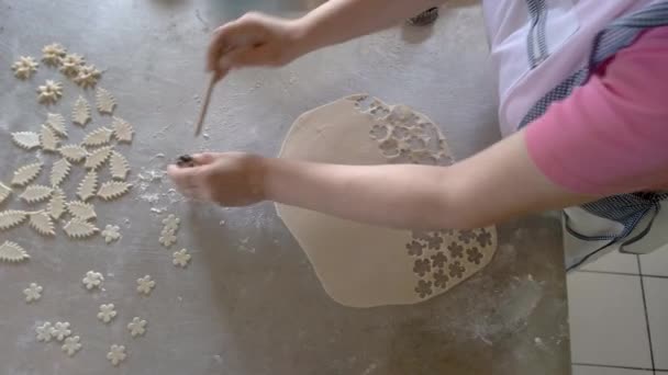 Vrouw snijdt kleine bloemen van deeg. — Stockvideo