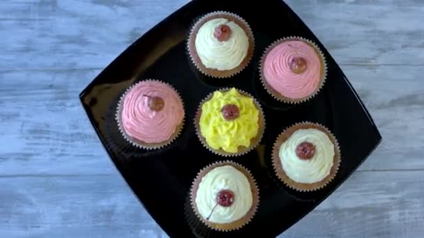 Verschiedene Cupcakes auf schwarzem Teller, Ansicht von oben. — Stockvideo