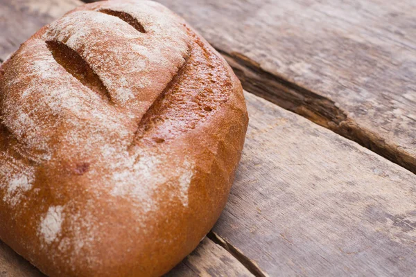 Whole loaf of a crispy bread on wooden background. — Stock Photo, Image