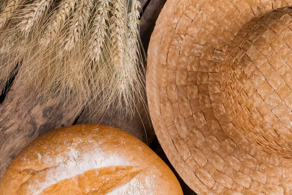 Wheat ears, bread and straw hat close up.
